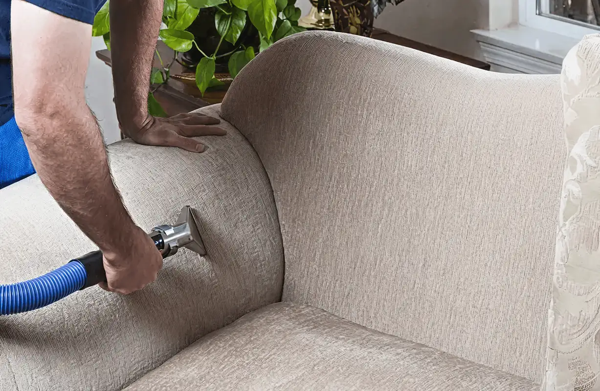 Professional upholstery cleaner deep-cleaning a fabric sofa with a handheld extraction tool and hose, Anaheim, CA.